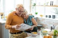 Smiling nice-appealing aged white-haired married couple reading a newspaper together