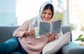 Reading is her favourite pasttime. an attractive young woman enjoying a cup of coffee and reading her book while