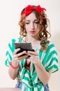 Reading & holding tablet pc computer beautiful blond young woman pinup girl with red lips & ribbon on her head on light background Royalty Free Stock Photo