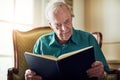 Reading keeps the mind strong. a senior man reading a book while relaxing at home.