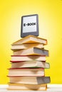 Reading and knowledge. E-book on top of a stack of books on a yellow background. Vertical. Concept of education and electronic Royalty Free Stock Photo