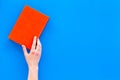 Reading for leasure. Hands take hardback book with empty cover on blue background top view space for text Royalty Free Stock Photo