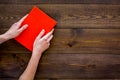 Reading for leasure. Hands take hardback book with empty cover on dark wooden background top view space for text