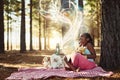 Reading lights up magical worlds for kids. a little girl reading a book with glowing pages in the woods. Royalty Free Stock Photo