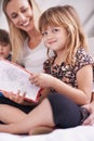 Reading, mom and daughter on sofa with book for bonding, teaching and learning together in home. Story, mother and child Royalty Free Stock Photo