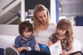 Reading, mother and children on couch with book for bonding, teaching and learning together in home. Woman, son and Royalty Free Stock Photo