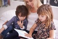 Reading, mother and children on couch with storytelling for bonding, teaching and learning together in home. Woman, son Royalty Free Stock Photo