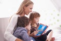 Reading, mother and children on sofa with story for bonding, teaching and learning together in home. Woman, son and Royalty Free Stock Photo