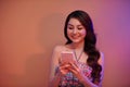 Reading new messages. Beautiful young Asian woman holding mobile phone while standing Royalty Free Stock Photo