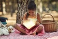 Reading is one way to nurture a childs curiosity. a little girl reading a book with glowing pages in the woods. Royalty Free Stock Photo