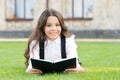 Reading is passport to world. Happy little girl enjoy reading book on green grass. Cute small child learn reading at Royalty Free Stock Photo