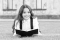 Reading is passport to world. Happy little girl enjoy reading book on green grass. Cute small child learn reading at Royalty Free Stock Photo