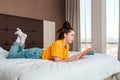 Reading and recreation. A young pretty woman is lying on the bed and reading a magazine. Windows on the background. Home  indoor Royalty Free Stock Photo