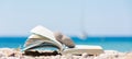 Reading in summer vacation, concept. Book on the pebble beach x Royalty Free Stock Photo