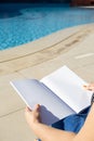 unrecognizable woman holding blank magazine for mockup design, sitting by the swimming pool Royalty Free Stock Photo