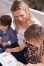 Reading, woman and children on sofa with book for bonding, teaching and learning together in home. Mother, son and Royalty Free Stock Photo