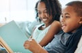 When he reads and makes everything funny. a little brother and sister reading a book indoors. Royalty Free Stock Photo