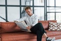 Reads newspaper. Caucasian young guy in elegant white shirt indoors at home Royalty Free Stock Photo