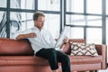 Reads newspaper. Caucasian young guy in elegant white shirt indoors at home Royalty Free Stock Photo