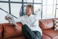 Reads newspaper. Caucasian young guy in elegant white shirt indoors at home Royalty Free Stock Photo