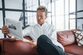 Reads newspaper. Caucasian young guy in elegant white shirt indoors at home Royalty Free Stock Photo