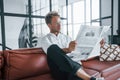 Reads newspaper. Caucasian young guy in elegant white shirt indoors at home Royalty Free Stock Photo