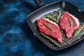 Ready for cooking raw rump or sirloin beef meat steak in a grill skillet. Blue background. Top view. Copy space Royalty Free Stock Photo