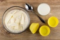 Ready flour mixture with butter for muffins in bowl, spoon, silicone molds, cup of milk on table. Top view