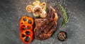 Ready juicy beef steak on a dark metal cutting board, next to a sprig of aromatic rosemary, a black jar of mixed peppercorns, Royalty Free Stock Photo