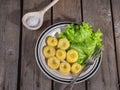 Ready-made potato gnocchi with leaves of fresh leaf lettuce on a ceramic plate with stripes, a table fork and a spoon on a plank Royalty Free Stock Photo