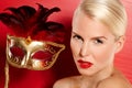 Ready for a masked ball. Portrait of a glamourous beautiful blonde woman holding up a gold venetian mask.