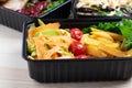 Ready meal to eat in containers with fried chicken wings and raw vegetables on rustic background, cherry tomato and micro greenss