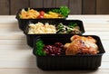 Ready meals to eat, containers with fried chicken wings and raw vegetables on rustic background, cherry tomato and micro greenss