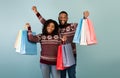 Ready for New Year celebration. Happy african american couple holding many colorful shopping bags over blue background Royalty Free Stock Photo