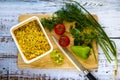 Ready noodles in bowl with chopped vegetables and herbs on a wooden board.