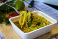 Ready noodles with vegetables and herbs on a wooden board.