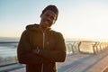 Ready for running. Happy male african runner in black sportswear smiling at camera, he is standing on the bridge in the Royalty Free Stock Photo