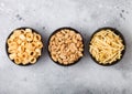 Ready salted potato rings with salt and vinegar sticks and roasted peanuts as classic snack in black bowls on light background