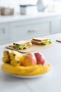 Ready sandwiches with cabbage and cheese lie on a wooden board in the kitchen. The plate with apples and bananas in the Royalty Free Stock Photo