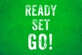 Ready Set Go! white words text on green grungy stucco cement wall background motivational message banner