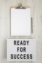 `Ready for success` words on a modern board, clipboard with blank sheet of paper on a white wooden background, top view. Overhea Royalty Free Stock Photo