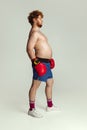 Funny red-headed man in blue boxing shorts and gloves isolated on gray studio background. Concept of sport, humor and