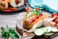 Ready-to-eat appetizing hot dog made from fried sausage, rolls and fresh vegetables, wrapped in parchment paper Royalty Free Stock Photo