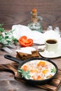 Ready-to-eat breakfast: shakshuka from fried eggs with tomatoes and parsley in a pan, bread with butter and coffeee Royalty Free Stock Photo