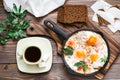 Ready-to-eat breakfast: shakshuka from fried eggs with tomatoes and parsley in a pan, bread with butter and coffeee Royalty Free Stock Photo