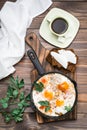 Ready-to-eat breakfast: shakshuka from fried eggs with tomatoes and parsley in a pan, bread with butter and coffeee Royalty Free Stock Photo