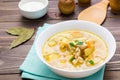 Ready-to-eat chicken soup with potatoes and herbs in a white bowl and sour cream