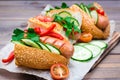 Ready-to-eat hot dogs from fried sausages, sesame buns and fresh vegetables on a cutting board Royalty Free Stock Photo