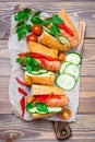Ready-to-eat hot dogs from fried sausages, sesame buns and fresh vegetables on a cutting board on a wooden table Royalty Free Stock Photo
