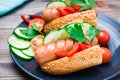 Ready-to-eat hot dogs from fried sausages, sesame buns and fresh vegetables on a plate on a wooden table Royalty Free Stock Photo